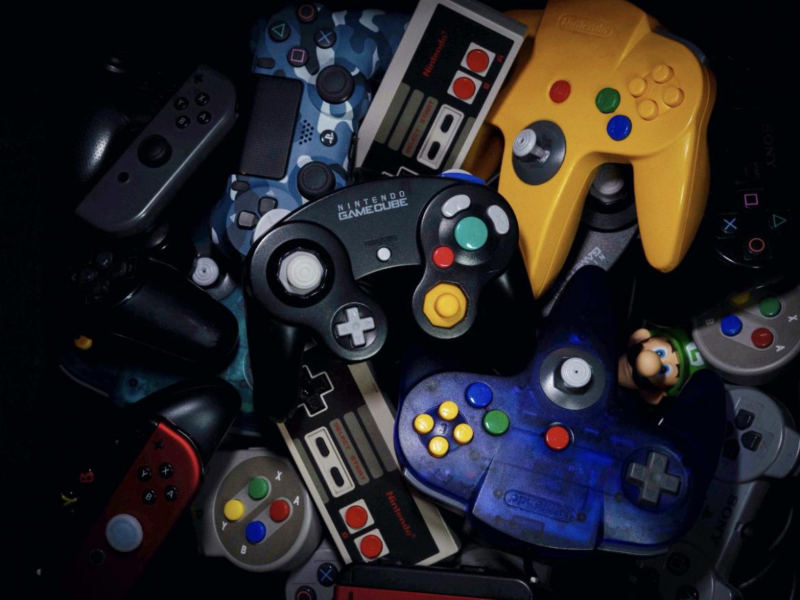 pile of vintage video game console controllers from the 1980s and 1990s