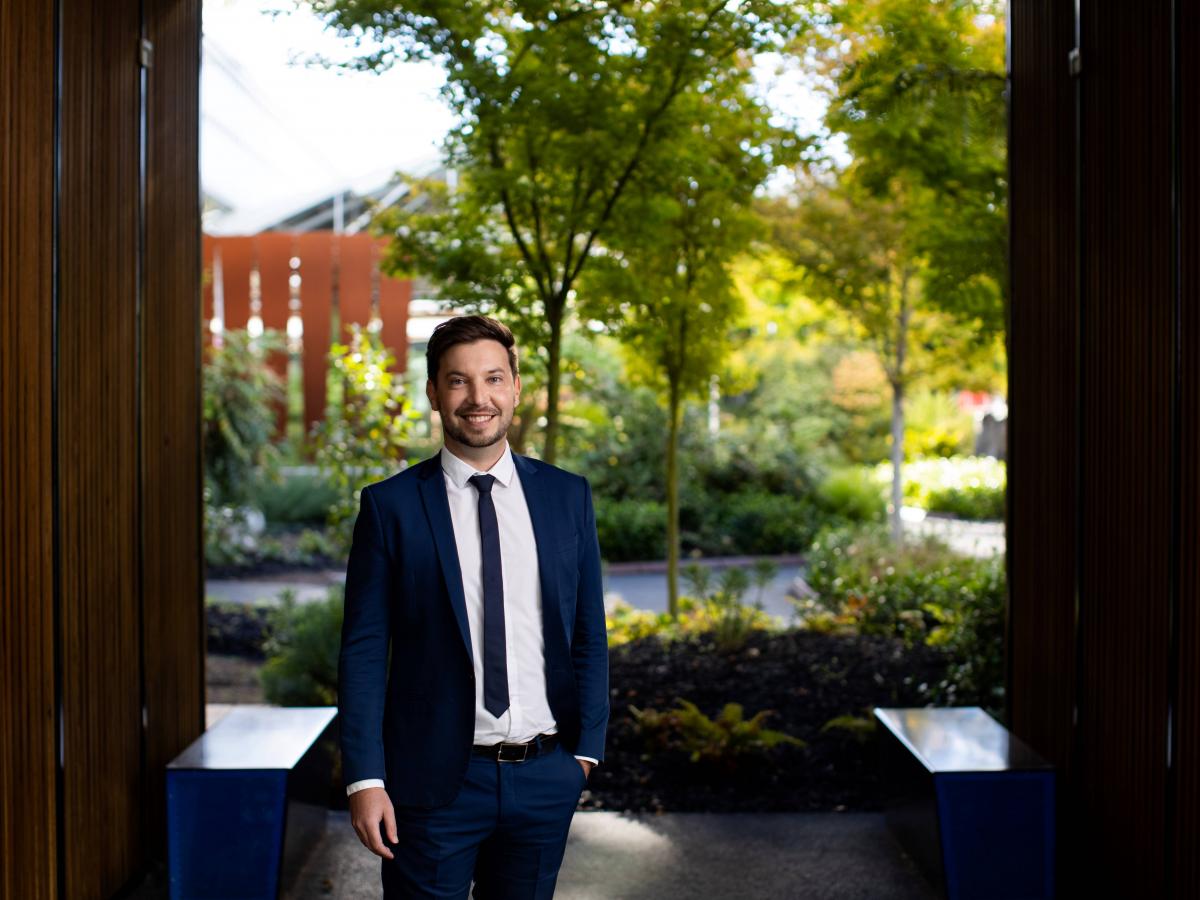 A photo of Ben in a suit, standing in a manicured garden