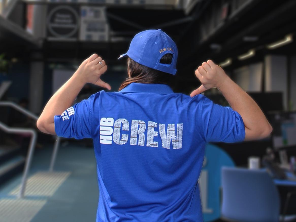 Person with back to camera wearing a blue Hub Crew t-shirt and cap