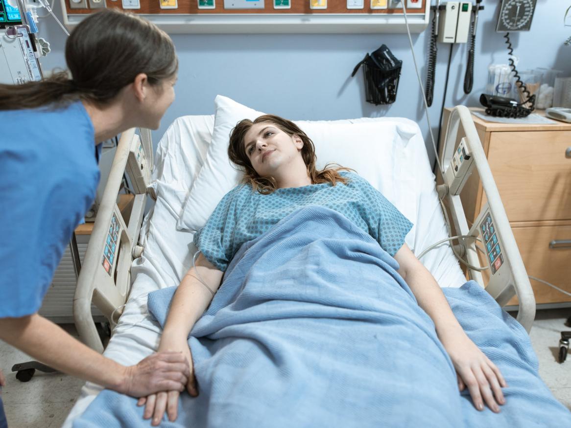 Doctor with patient lying on hospital bed