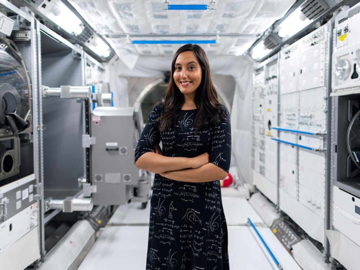 A female space engineer stands in front of technologies.