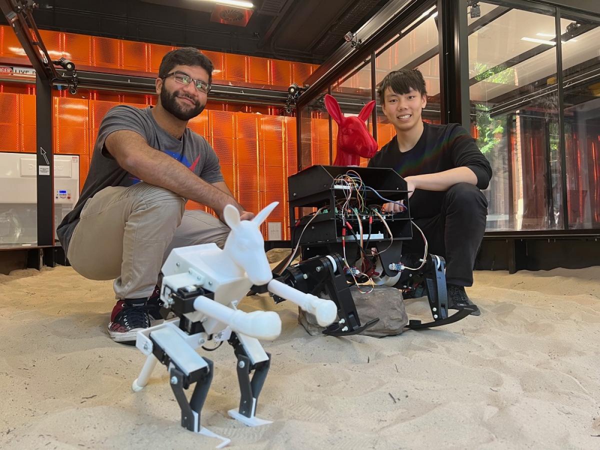 Vishwajit Pillay and Andy Tran pose with RooBot and JoeyBot, robots they made.