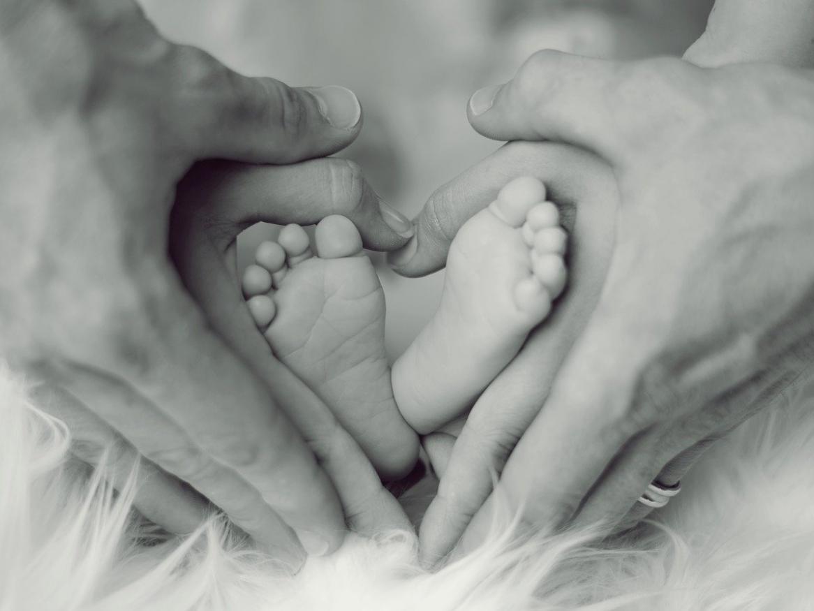 Baby feet held by hands of two adults