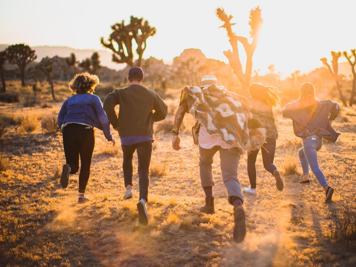 youth running away from camera in desert at sunset