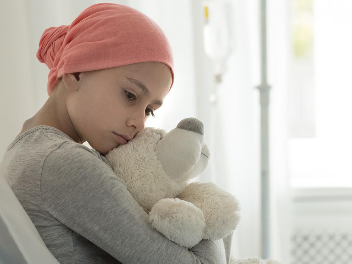 Child with cancer holding a stuffed toy
