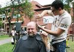 Professor Bob Hill holds his freshly cut ponytail as Grant Nelson, Manager of South 21 hairdressing salon, gives the professors remaining hair an all-important trim
Photo by David Ellis