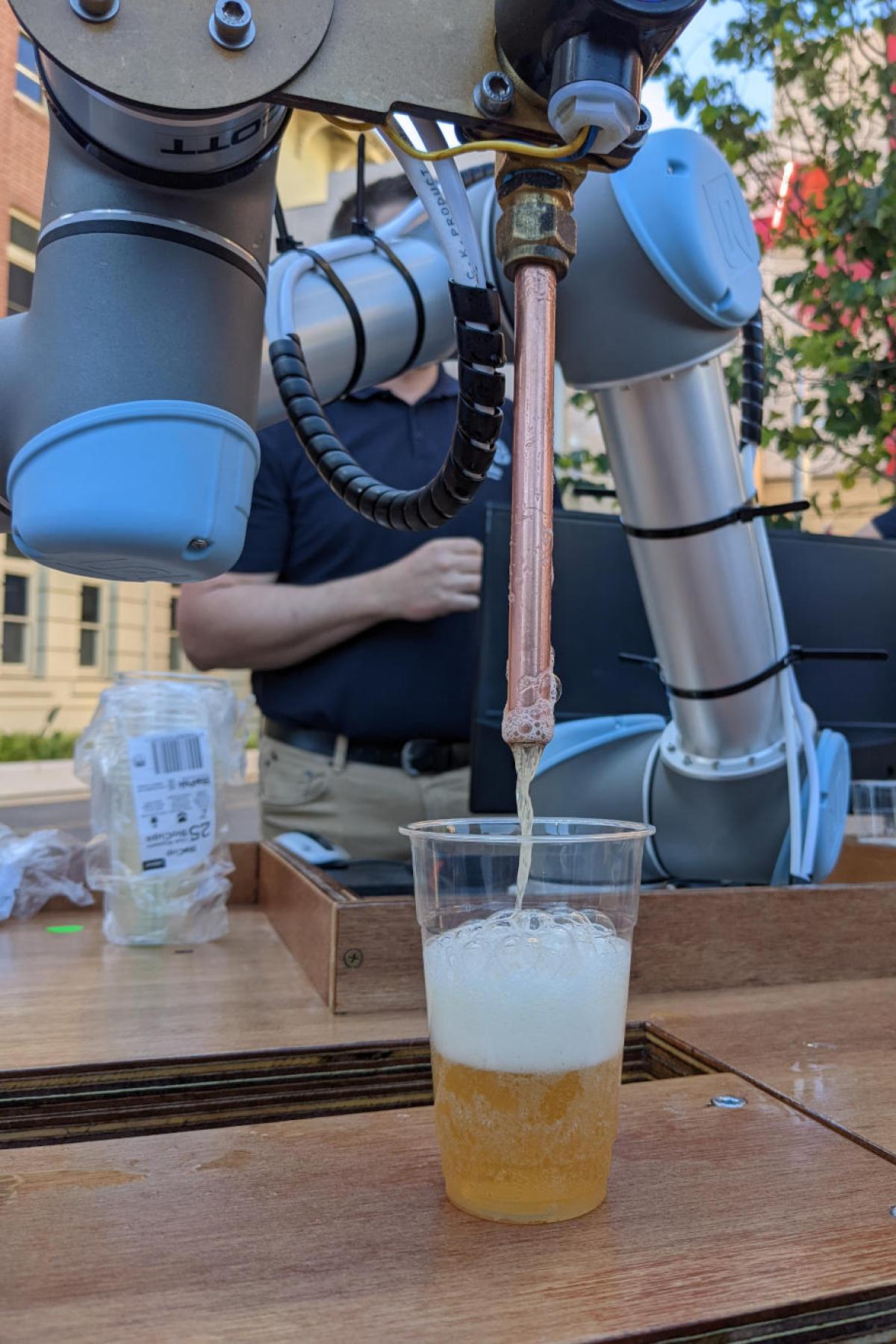 a robotic arm dispenses a beer into a plastic cup