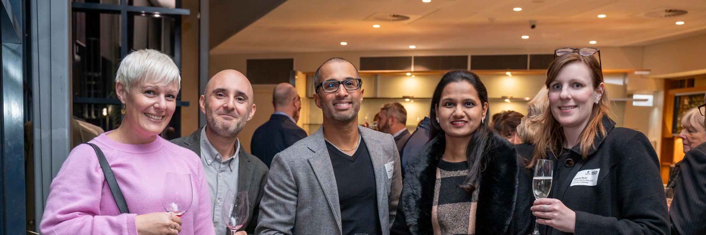 Five MBA alumni smiling for the camera at an alumni network event