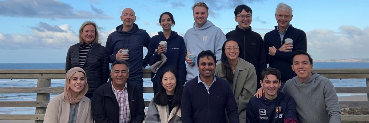 A large group of postgraduate students standing by the ocean in 2025
