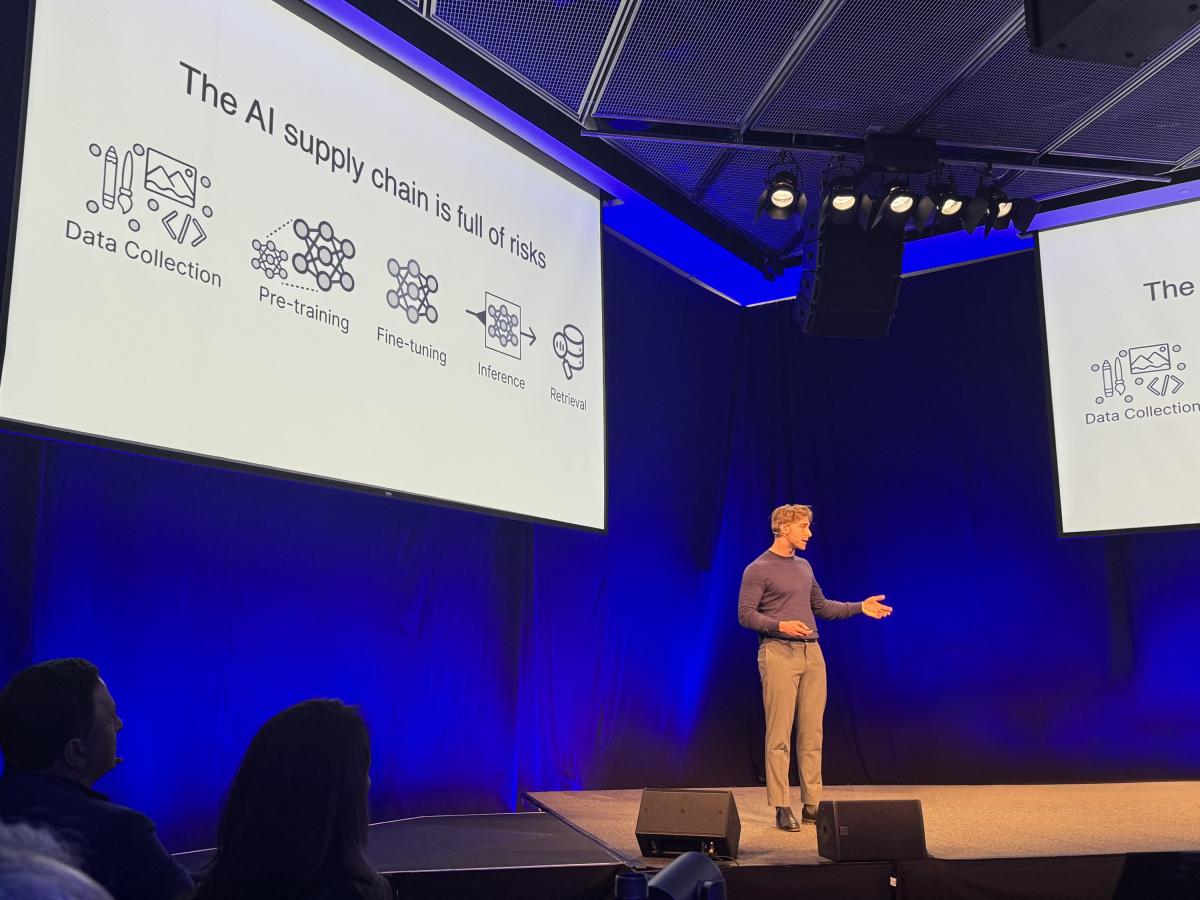 Tobin on stage talking, with slides about AI