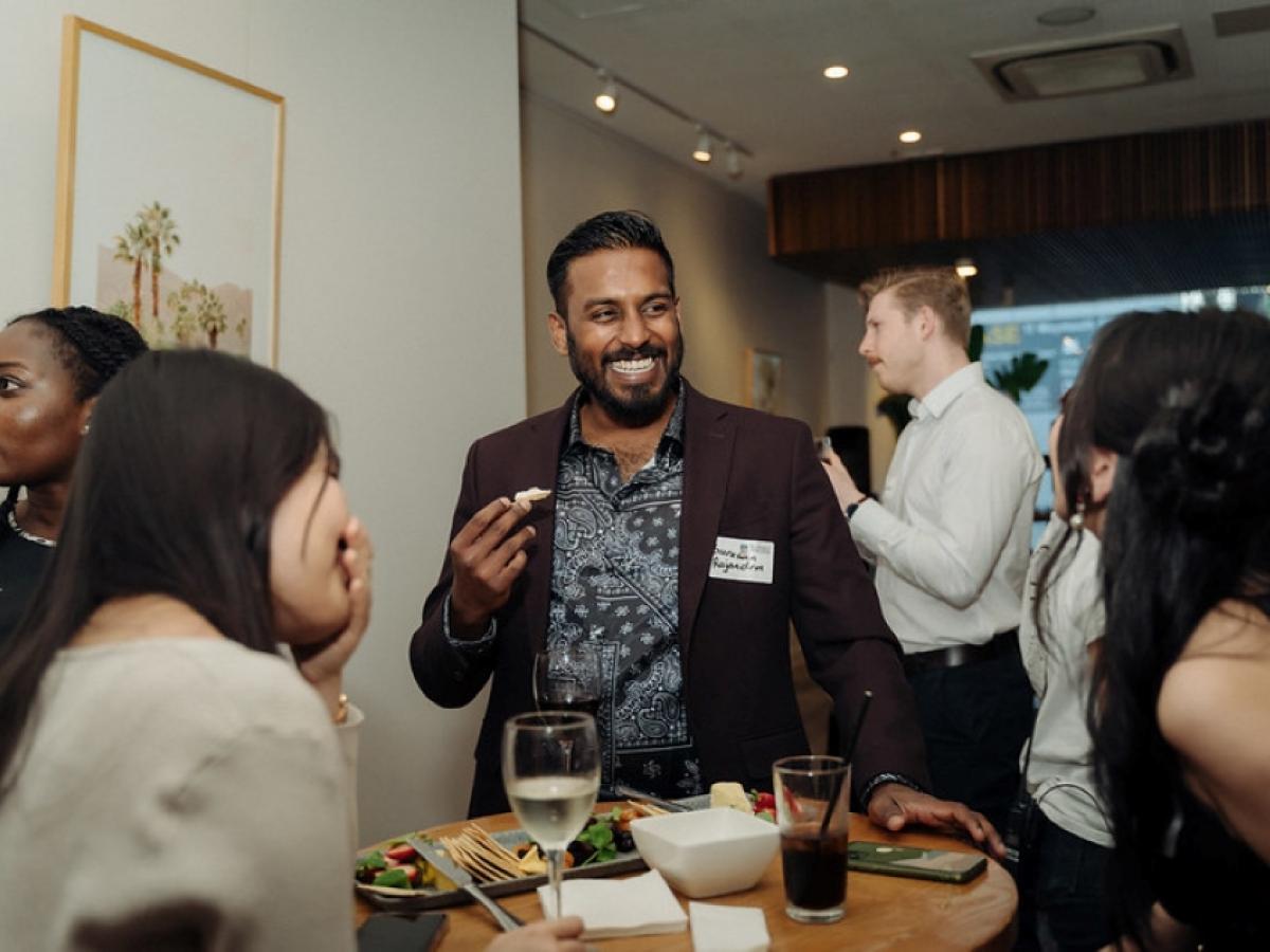 Three Young Alumni Network members laughing over snacks