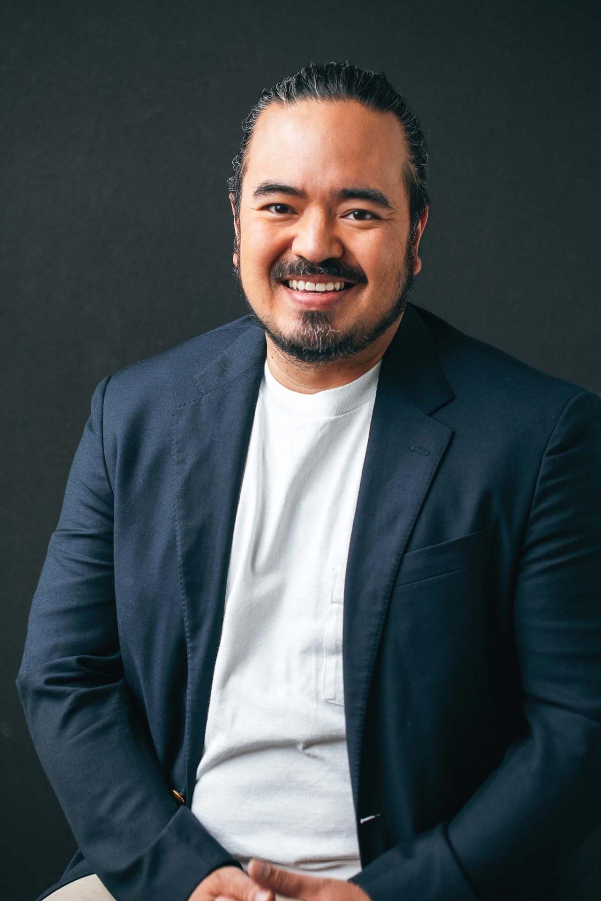 A portrait of Adam Liaw against a black backdrop