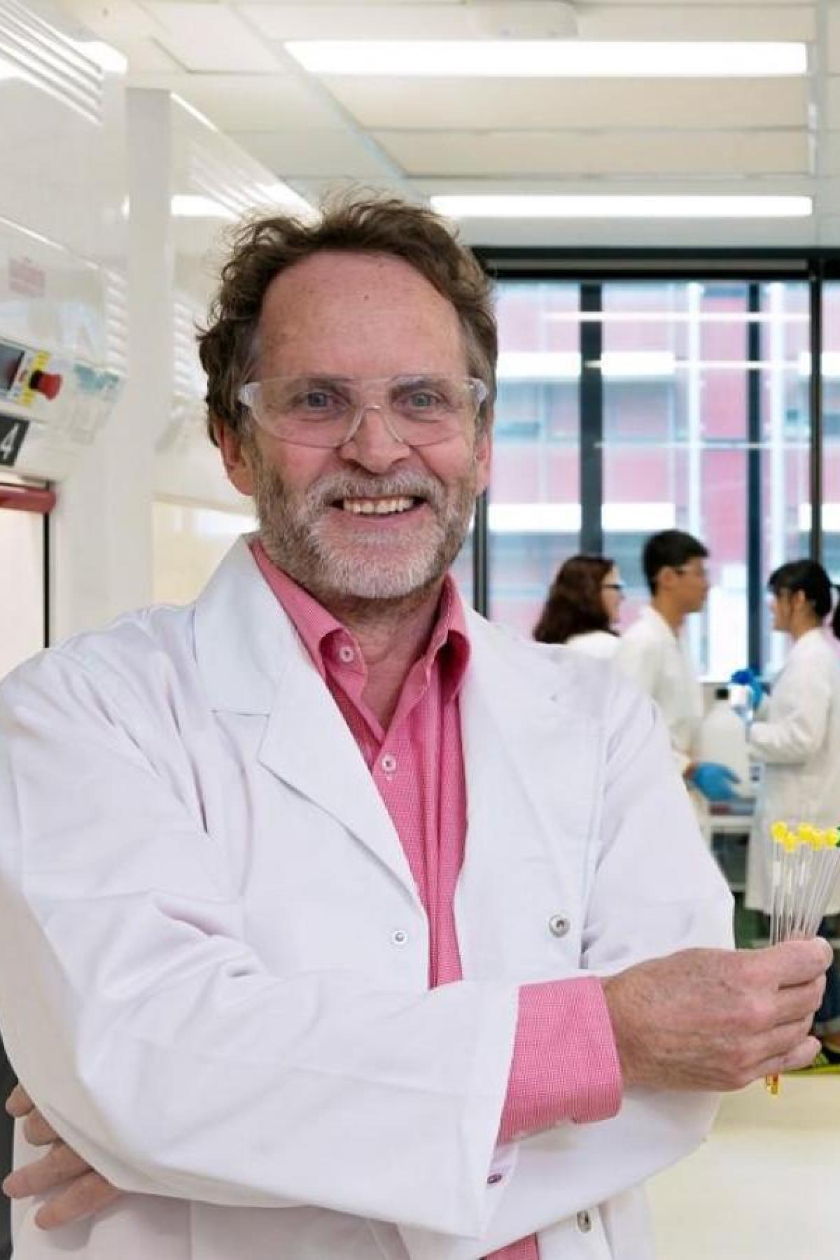 Prof Andrew Abell in a lab coat in a lab busy with researchers