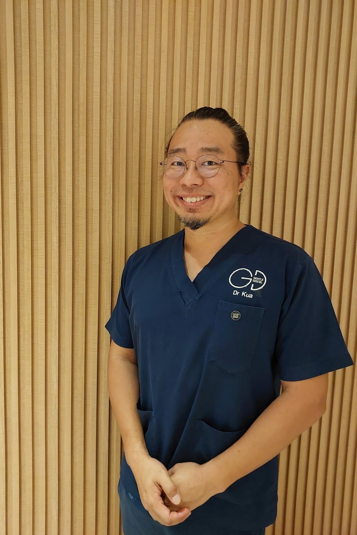 A picture of Dr Kua in his dental scrubs, smiling