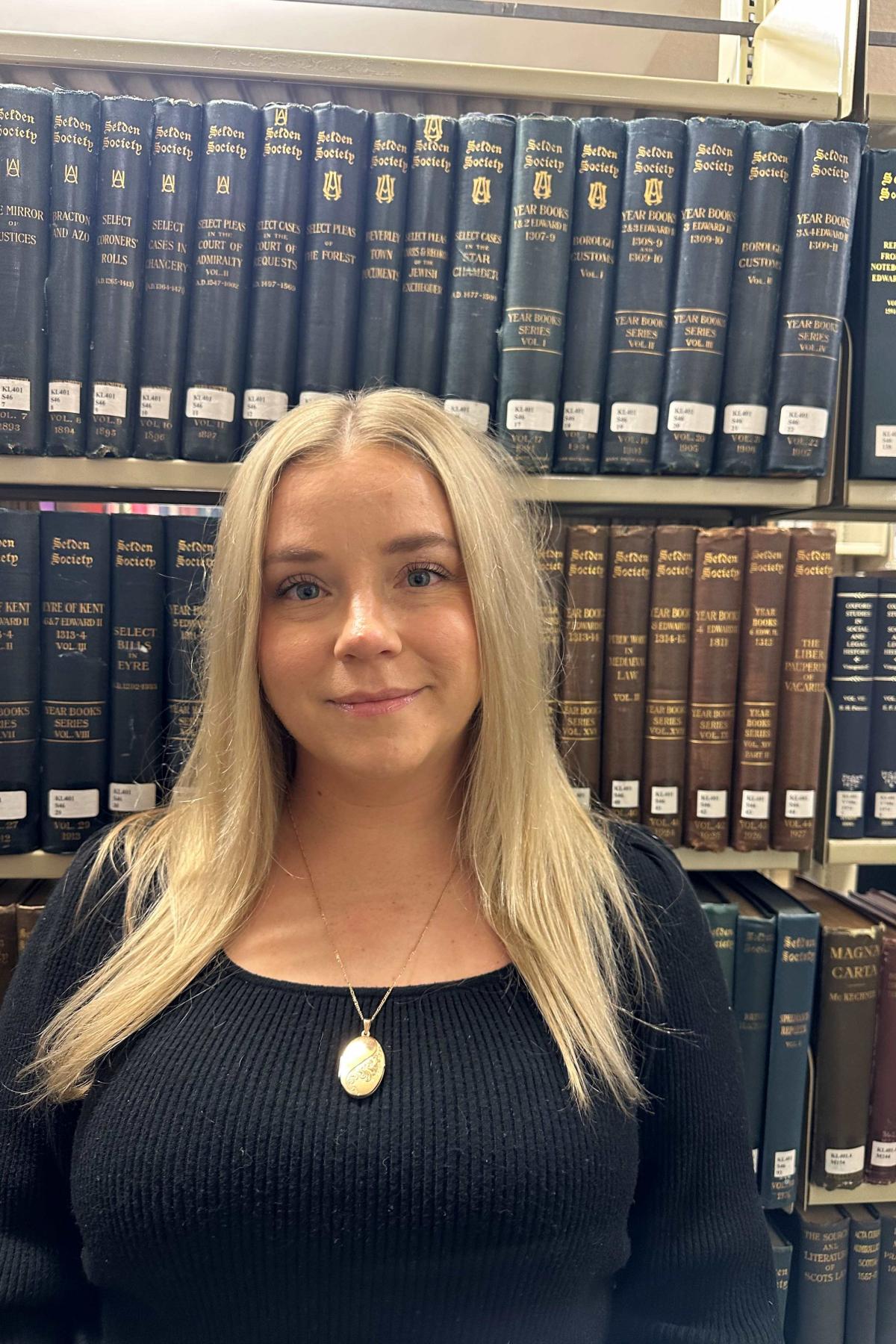A photo of Frankie in front of a bookshelf full of books