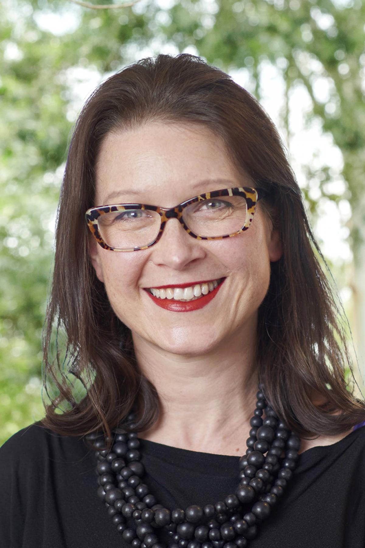 A portrait of Sarah Barker outside, smiling