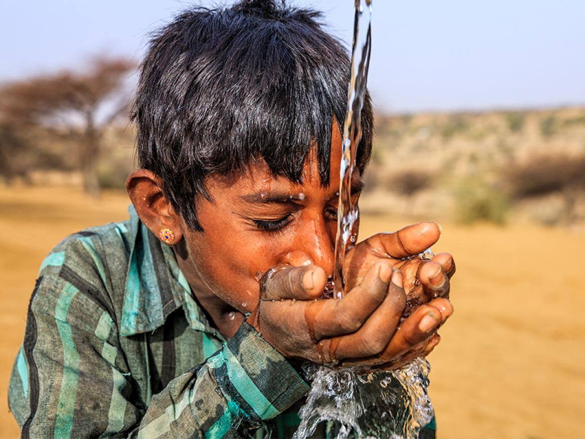 Photo of young boy drinking water in the desert region of Rajasthan, India