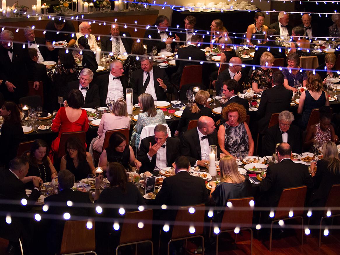 A photo from the inaugural Board of Benefactors Festum which shows people sitting on long tables under festoons of lights