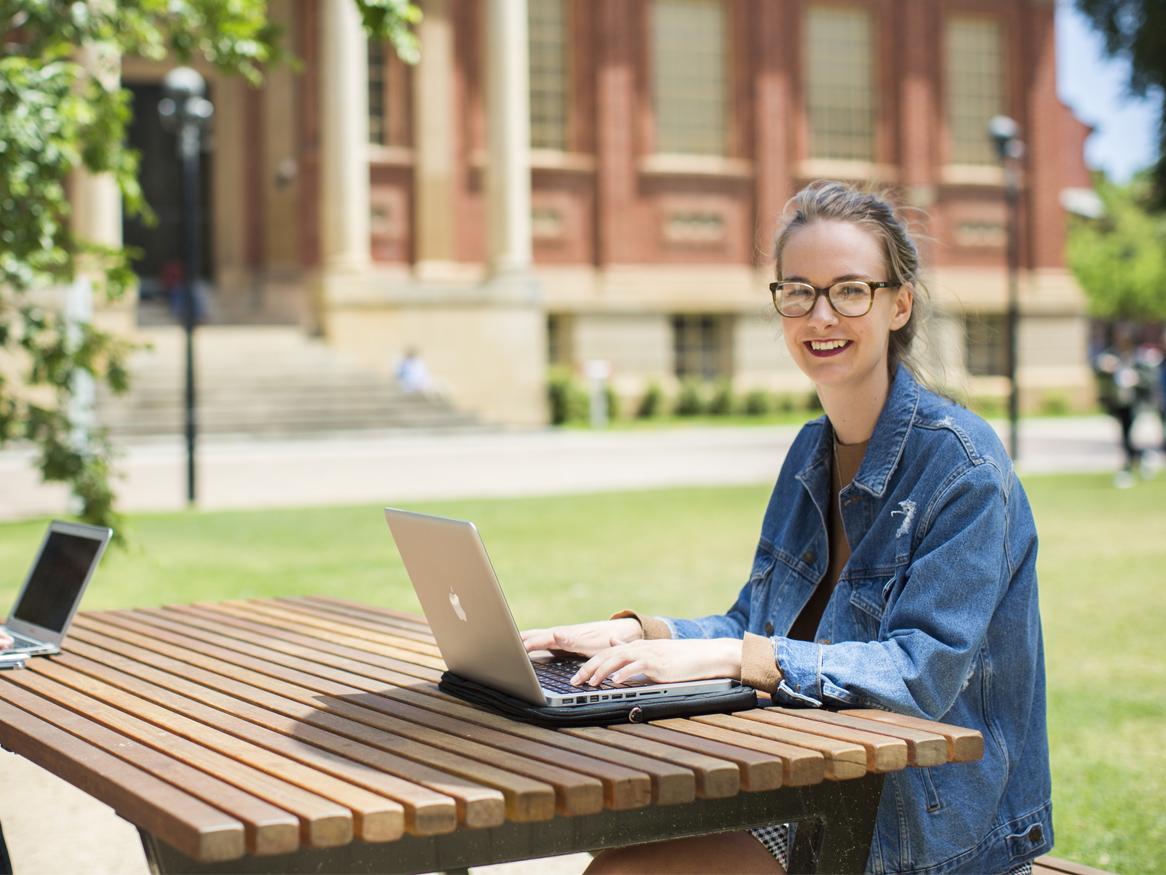 Student on laptop in front of Barr Smith Library
