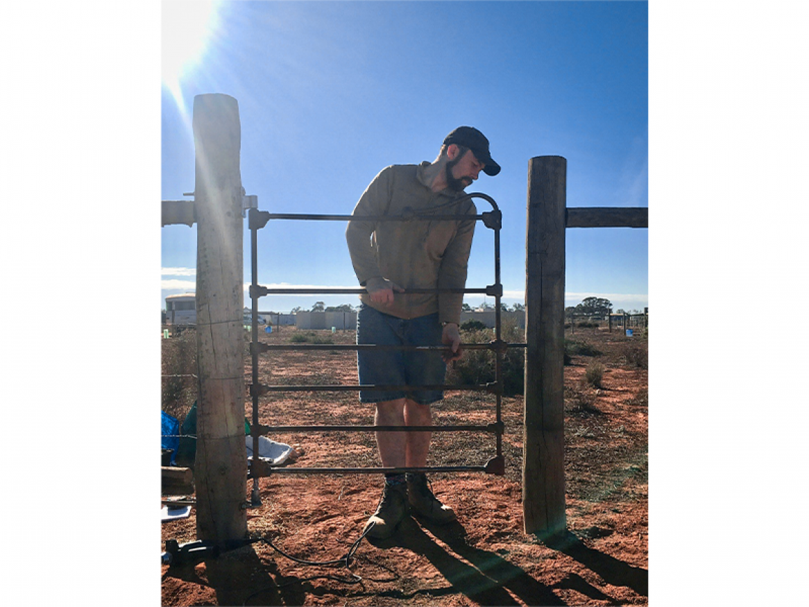 Alex hanging a gate on his property in the Murray Mallee where he is regenerating the land with his partner Aurelia