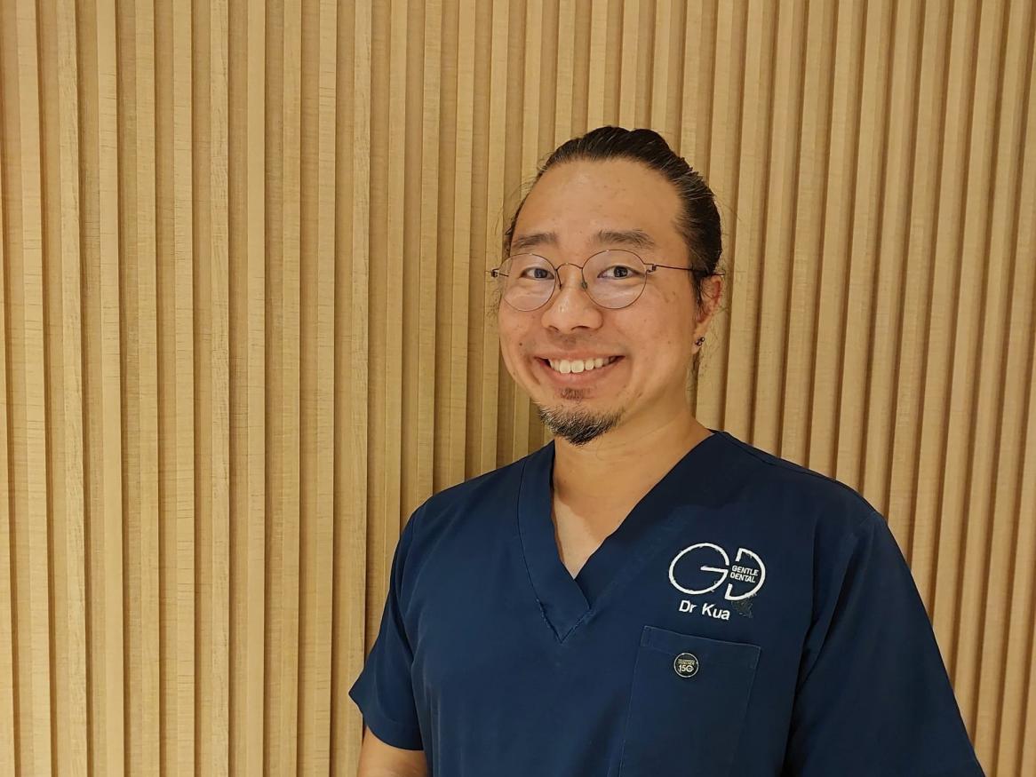 A picture of Dr Kua in his dental scrubs, smiling