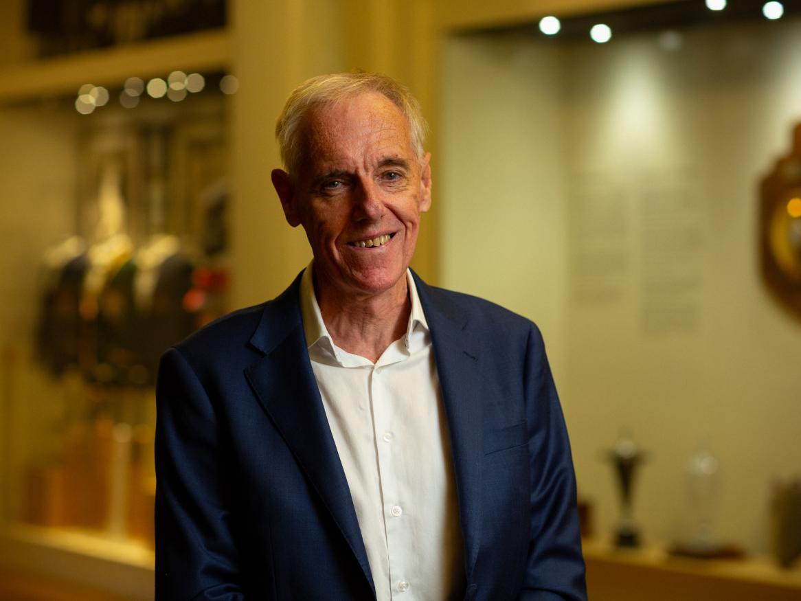 Graham Winter smiling in front of trophy cabinet 