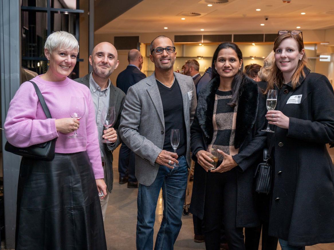 Five MBA alumni smiling for the camera at an alumni network event