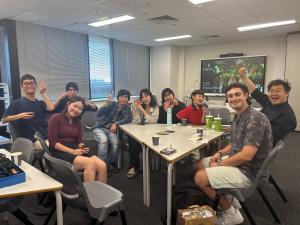 Landscape photo of various students playing Uno while eating Pizza