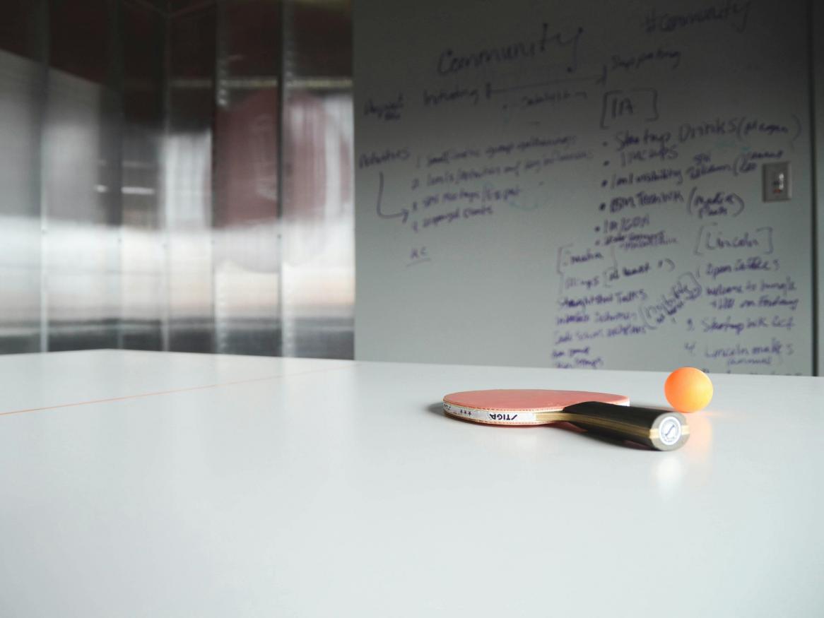 Photo of ping pong racket with ball and whiteboard in the background