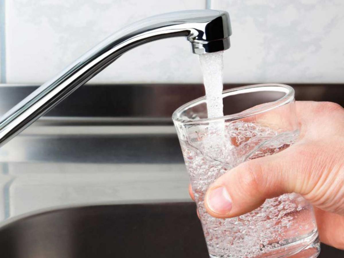 Filling a glass cup with water from a kitchen tap