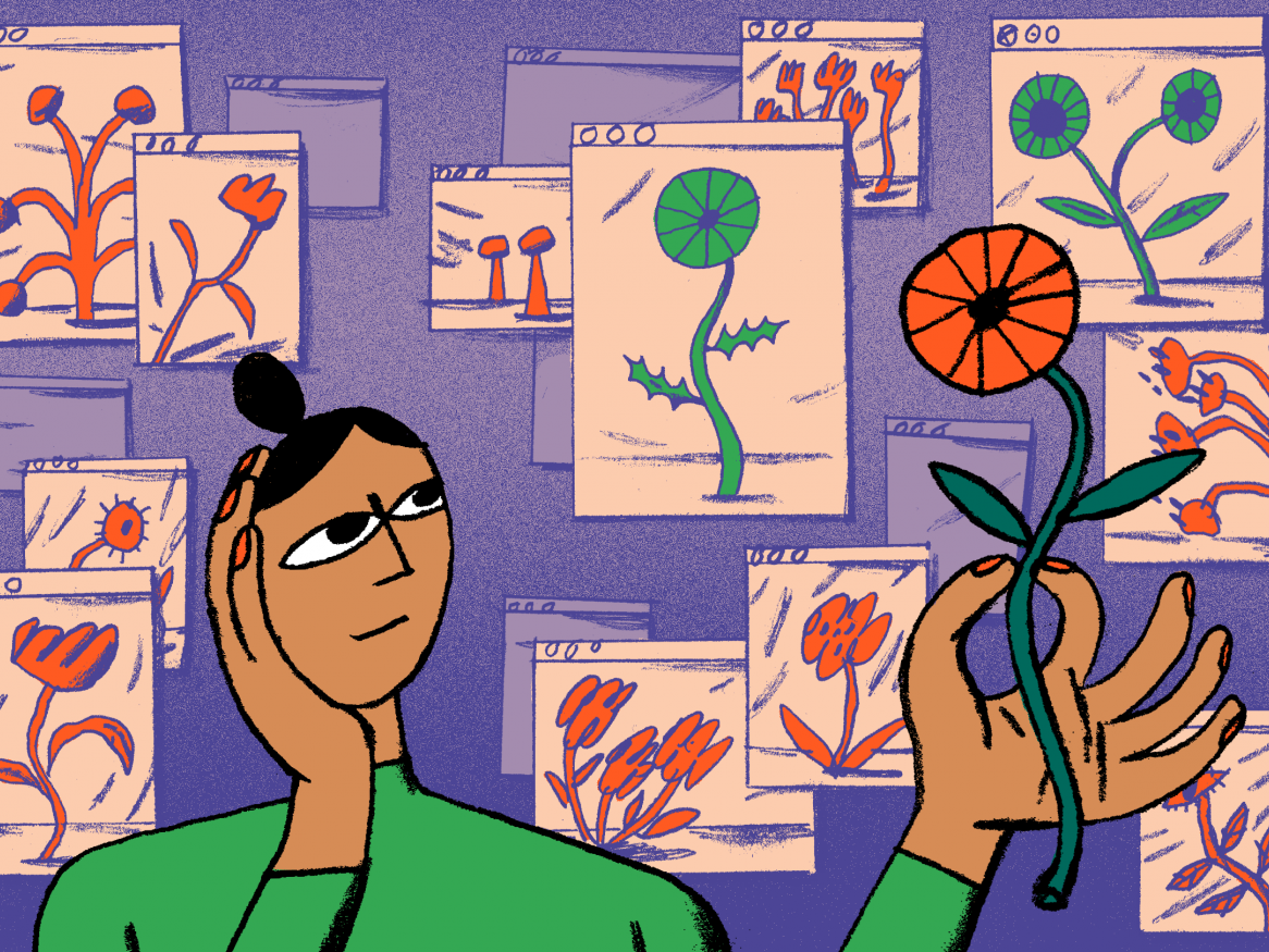 A person holding a flower in front of a wall covered in flower drawings. 