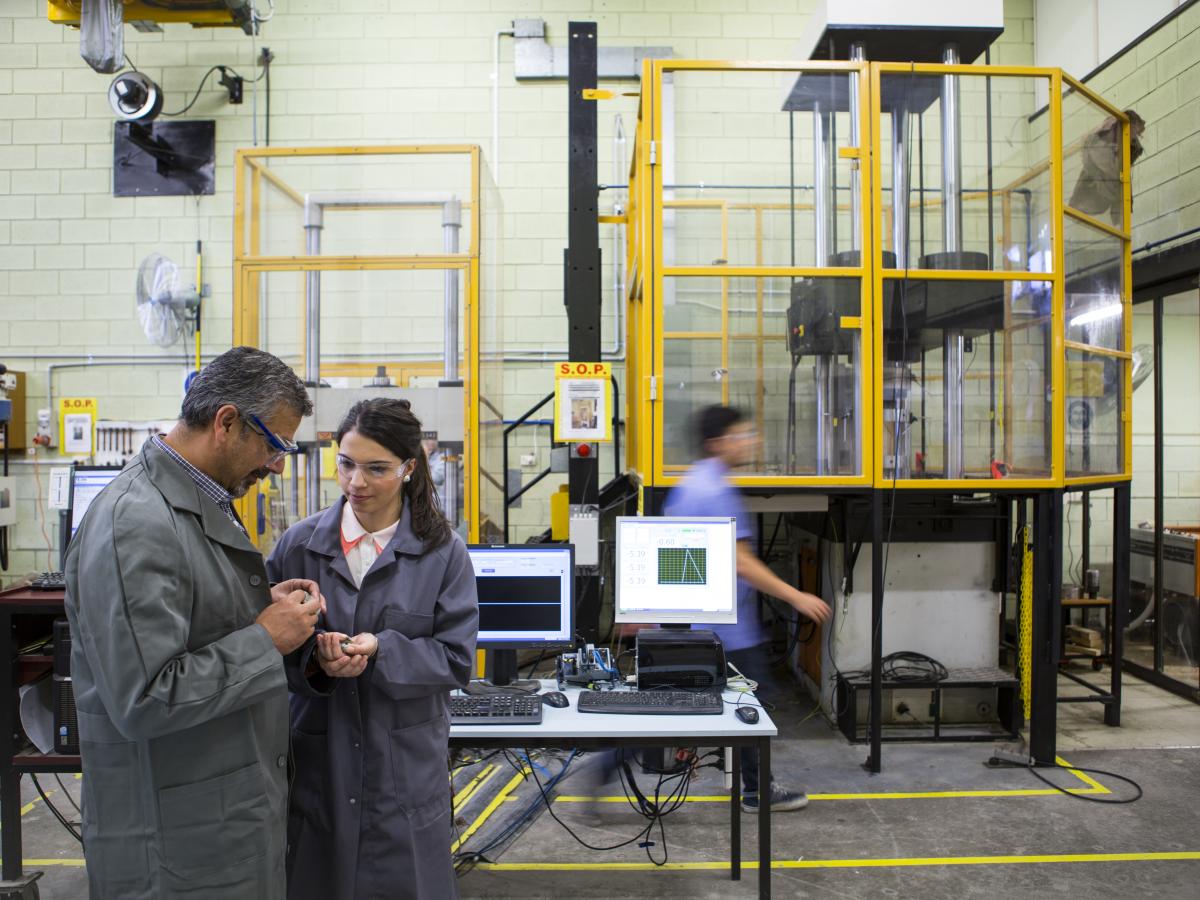 Male teacher and female student in mining engineering workshop.