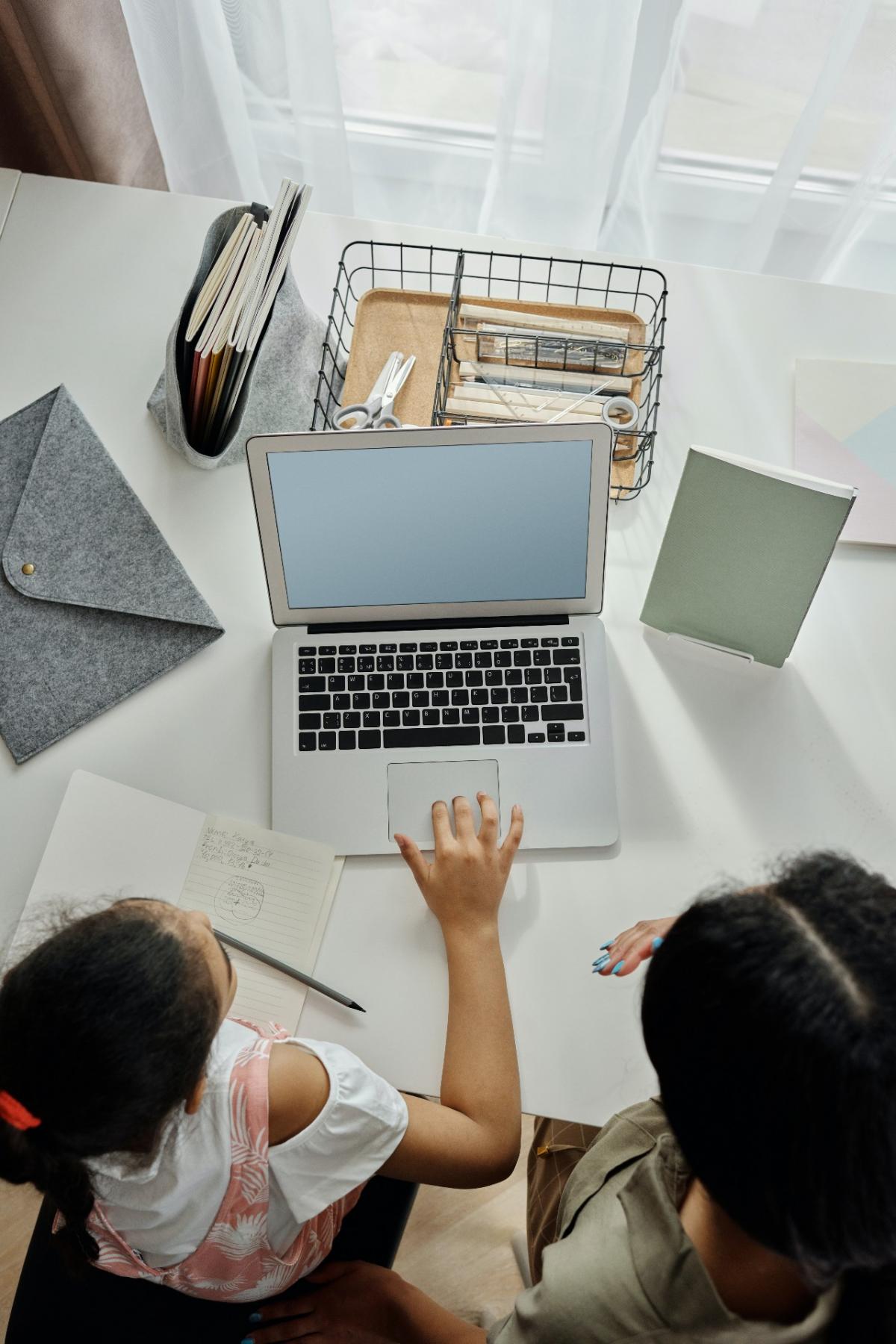 Mother and daughter sit at laptop.