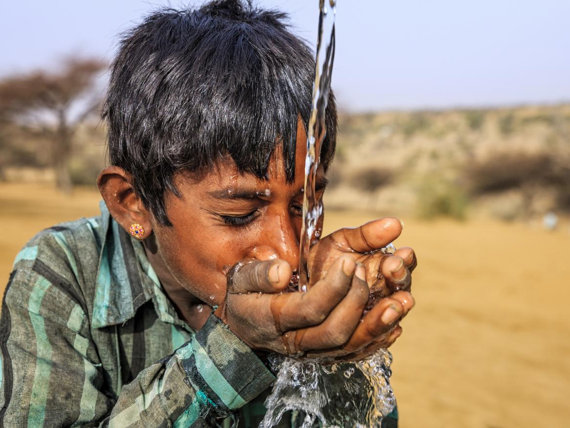 Photo of a young boy drinking water in the deserts of Rajasthan