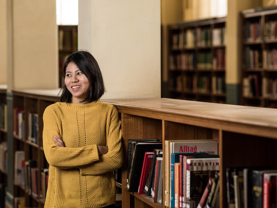 Young female alumni standing near bookshelves in the Barr Smith Library