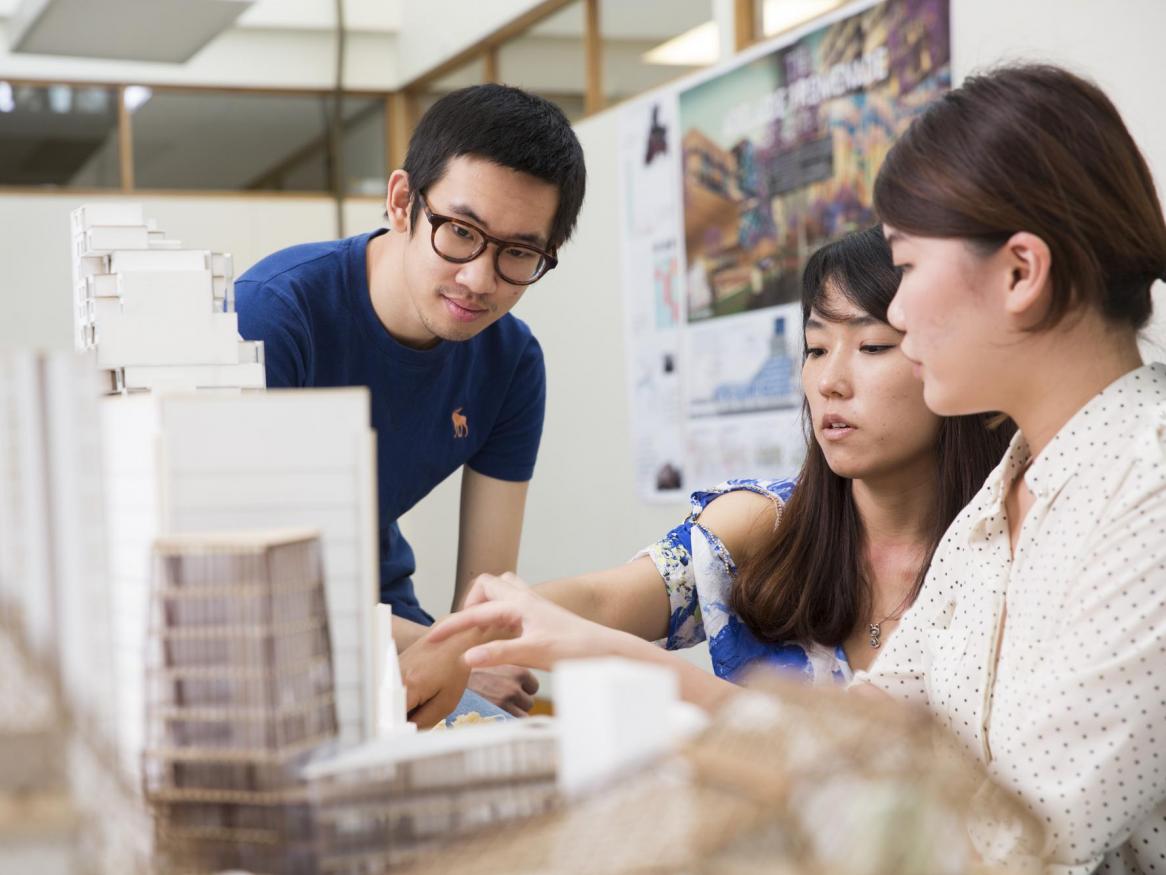 Three students inspect an architectural model