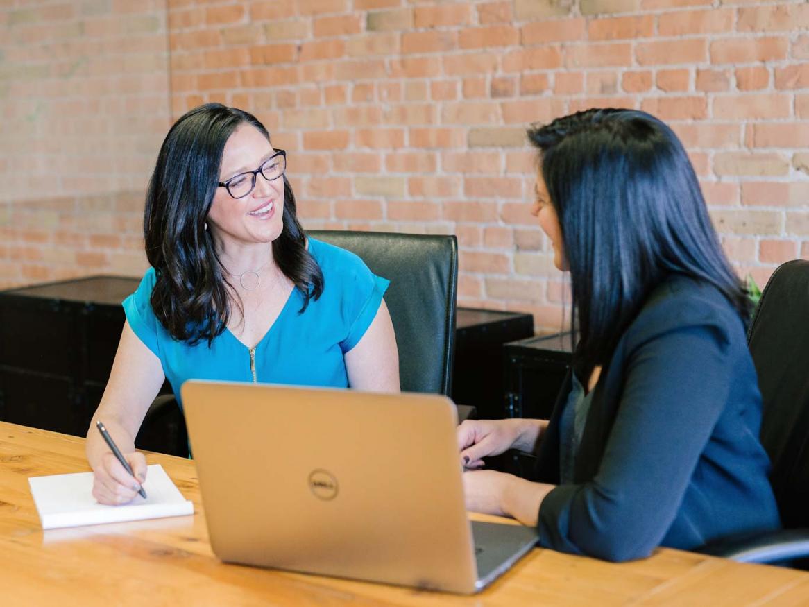 Two people talk in front of a computer