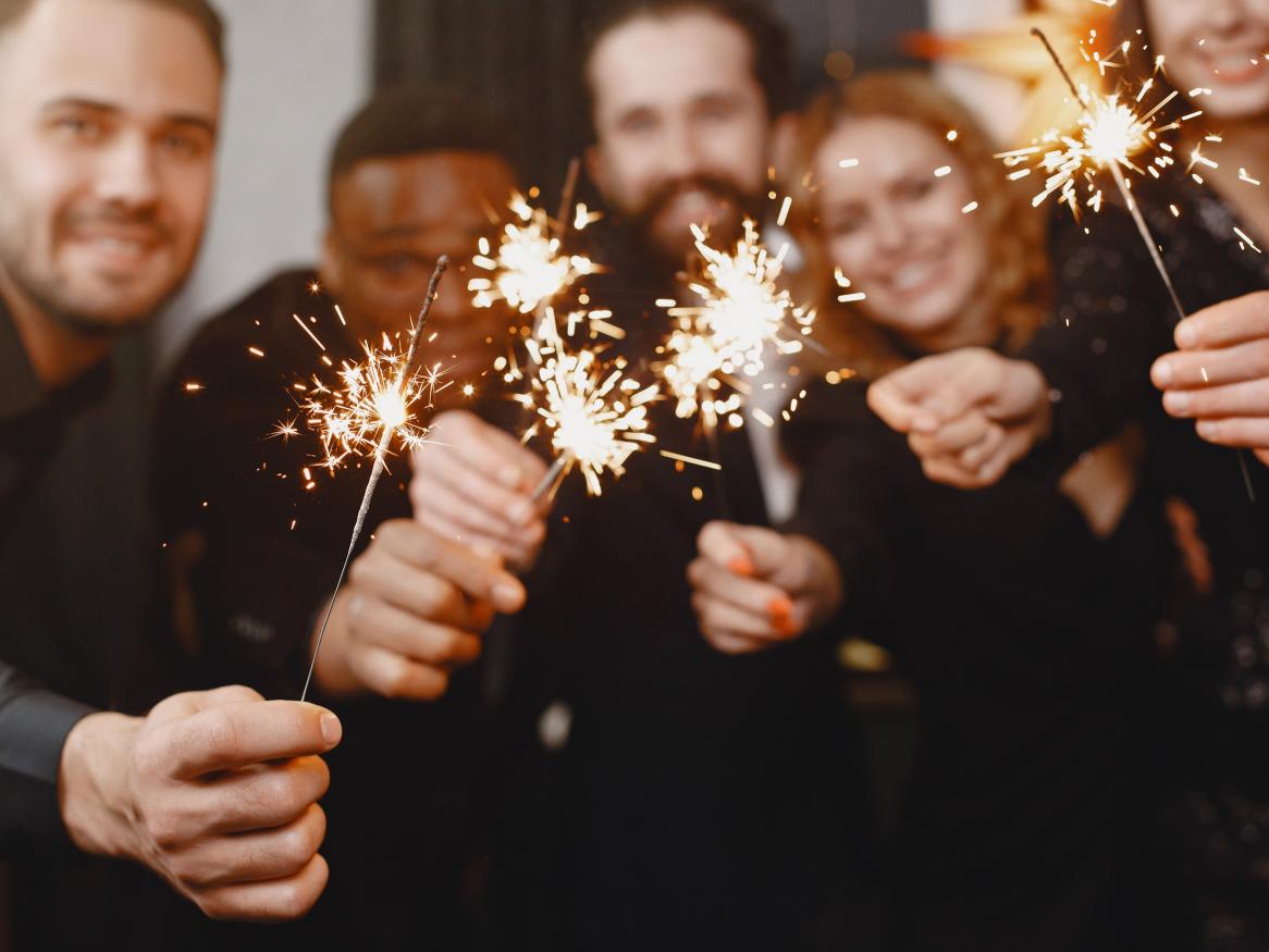 People dressed in black holding sparklers