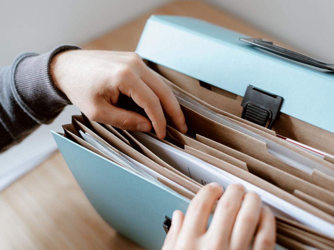 A person reaching into a blue accordion document folder
