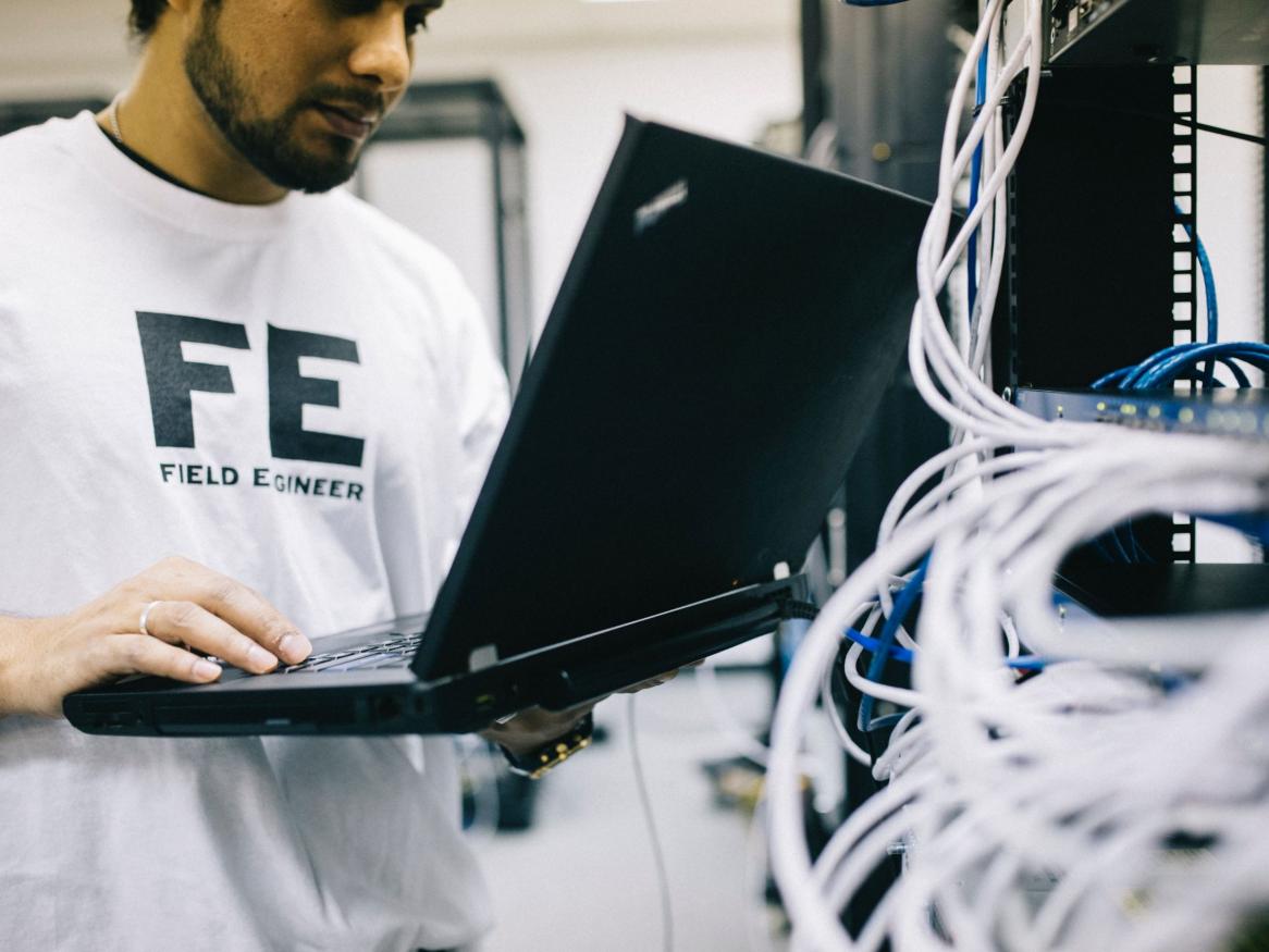 Person holding a laptop in front of computer system