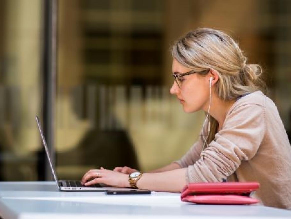 Female student studying outside with laptop