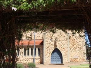 Photo of the exterior of the Roseworthy Chapel, looking through an arch formed by climbing plants.