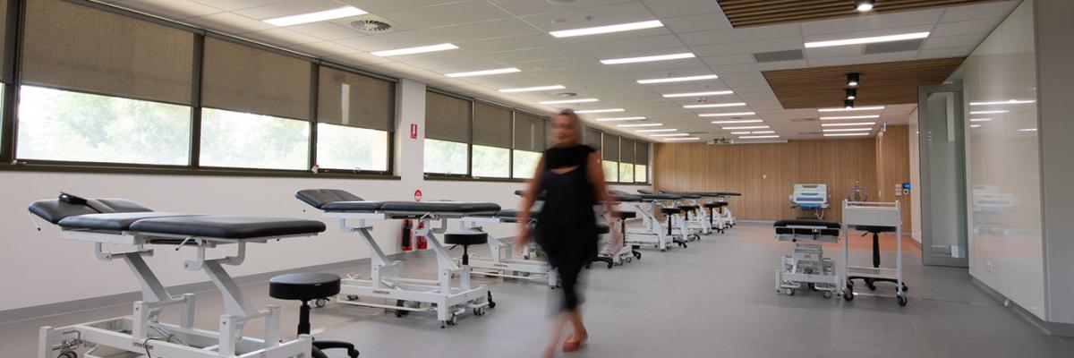 Allied Health person walking through completed room with hospital beds