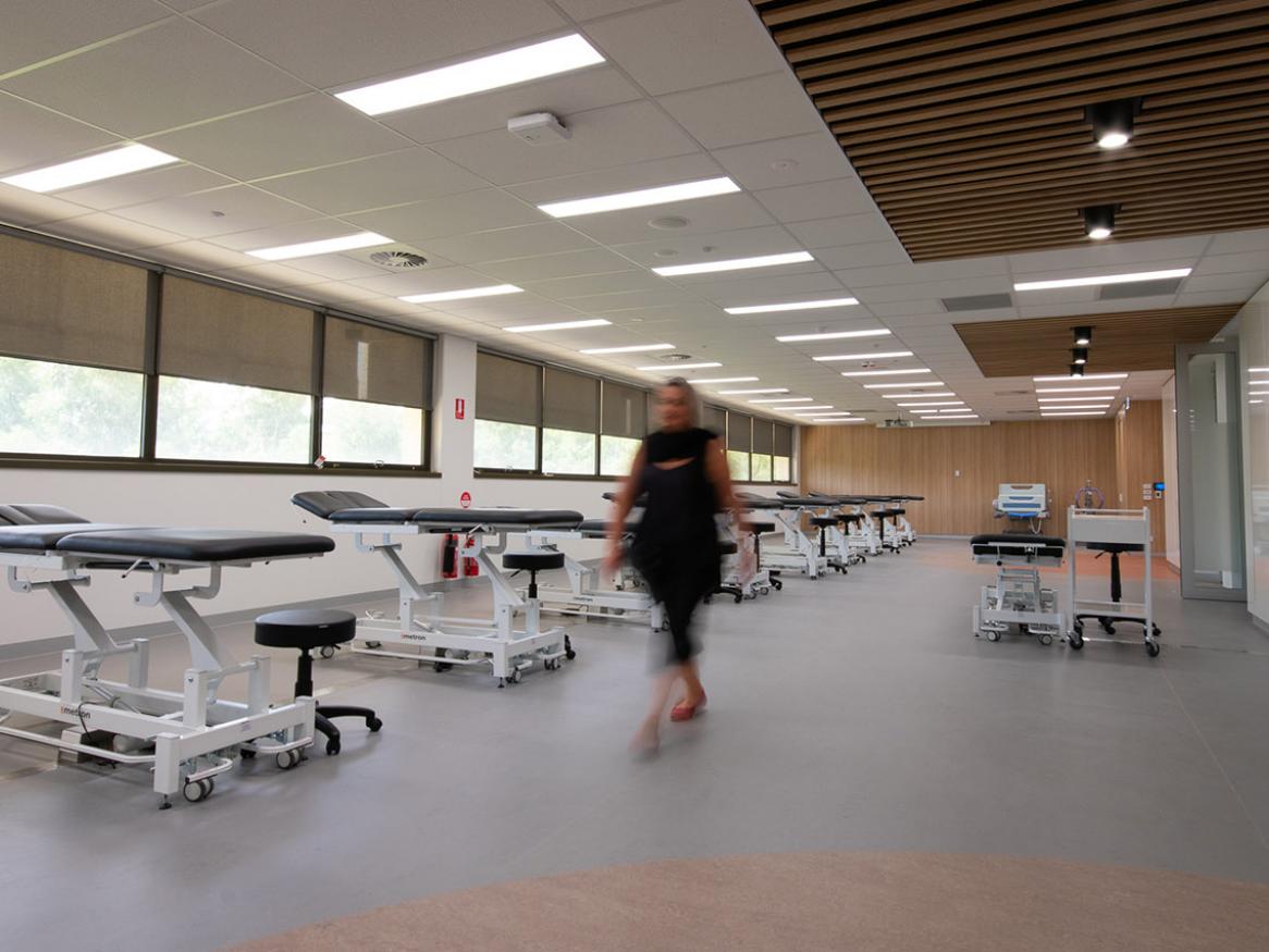 Allied Health person walking through completed room with hospital beds 