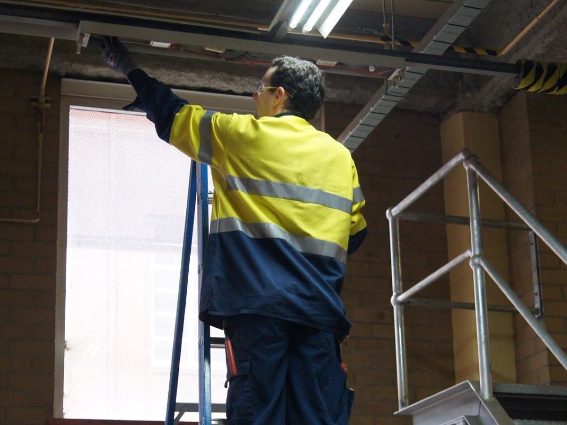 Contractor installing a light up a ladder