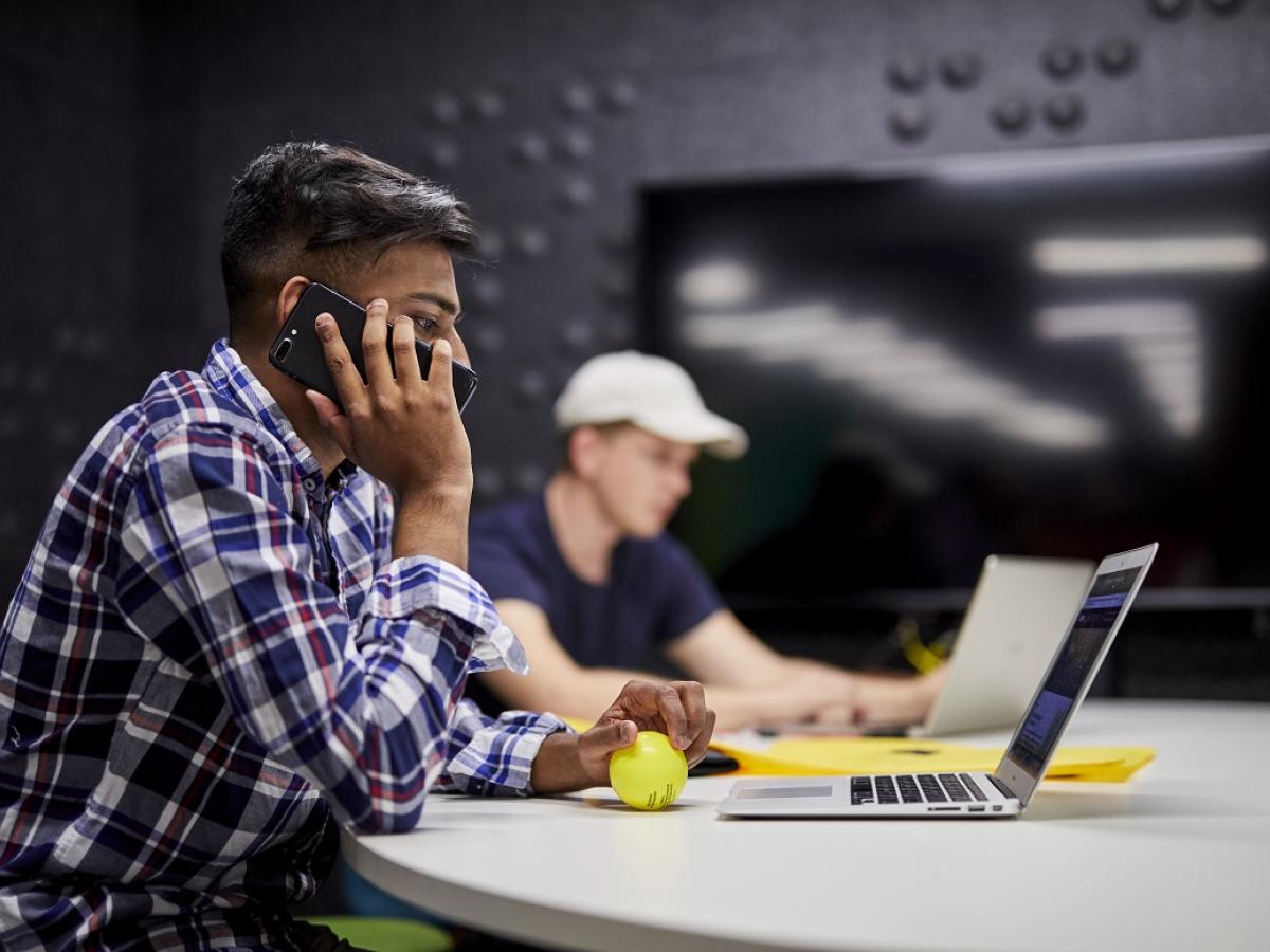 Student sitting at computer using the phone