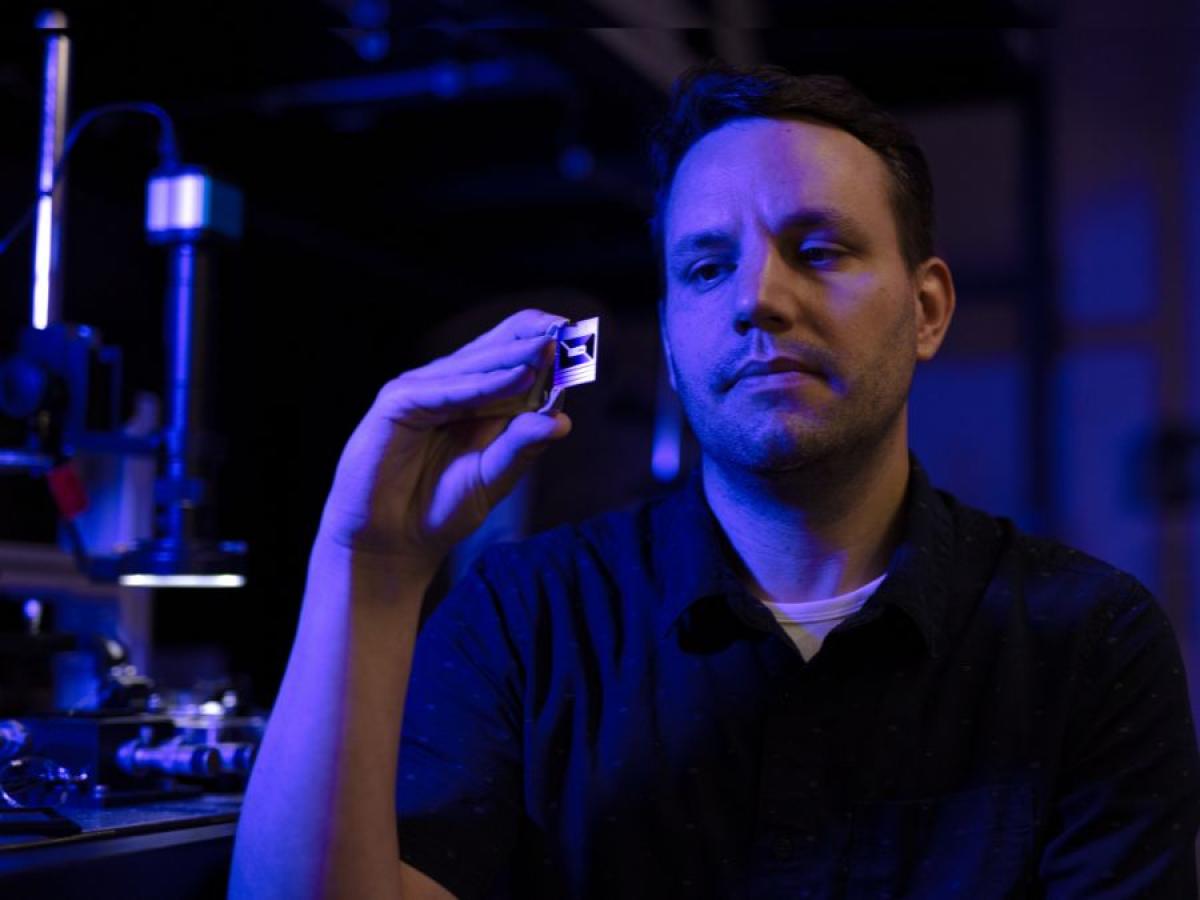 Andy Boes holding a Photonics Integrated Circuit (PIC) Chip