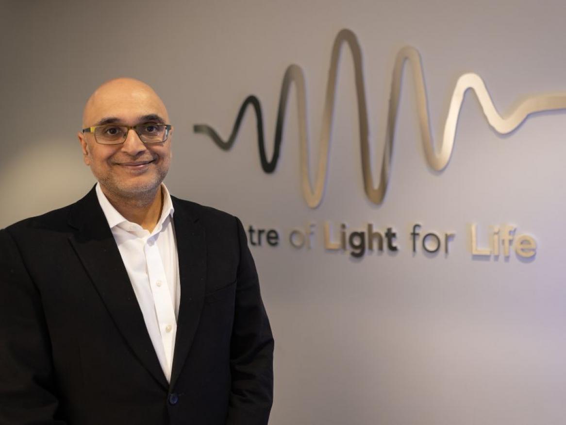 Prof Kishan Dholakia in front of the Centre of Light for Life's logo