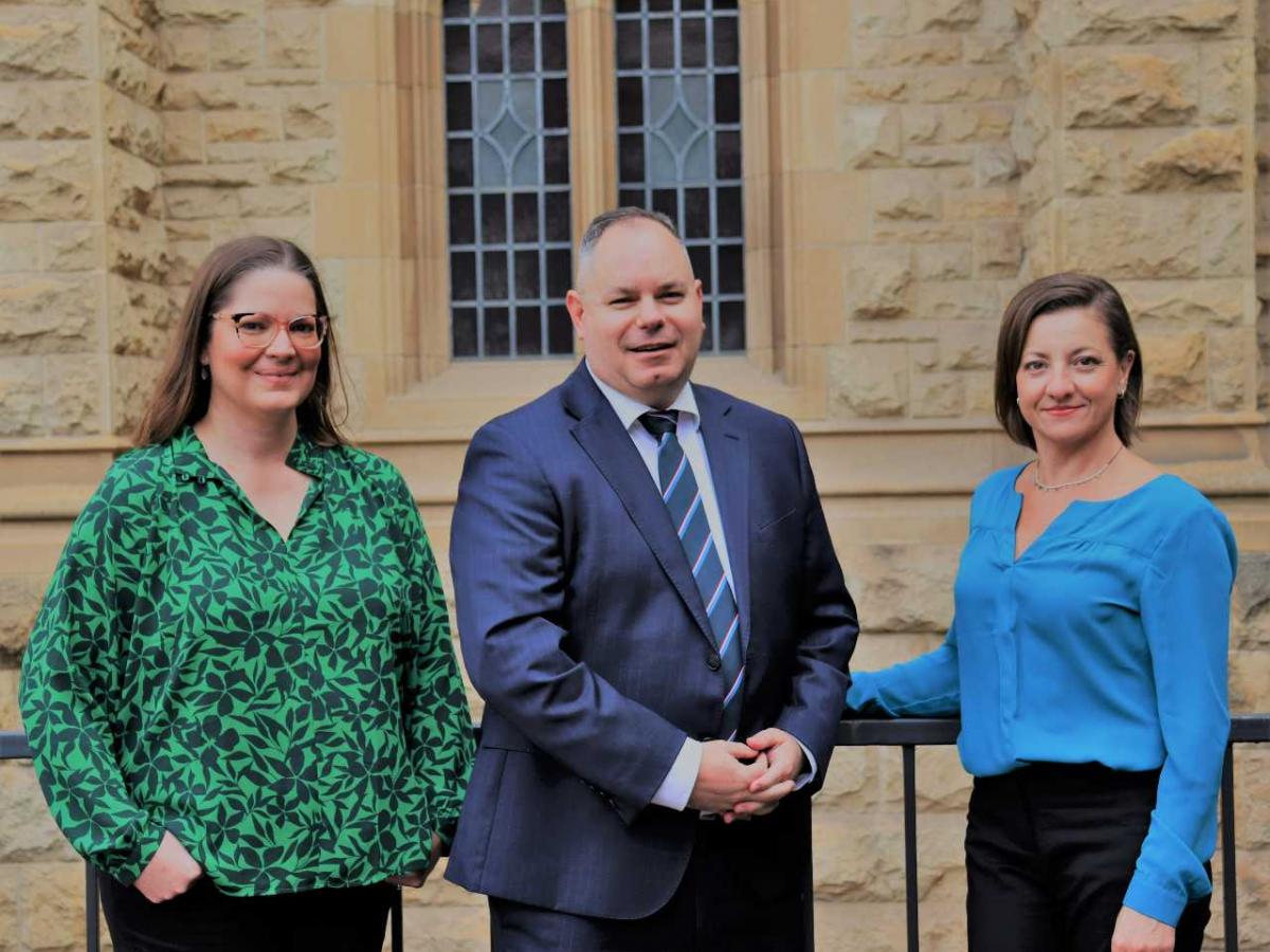 Two women and a man smiling at the camera