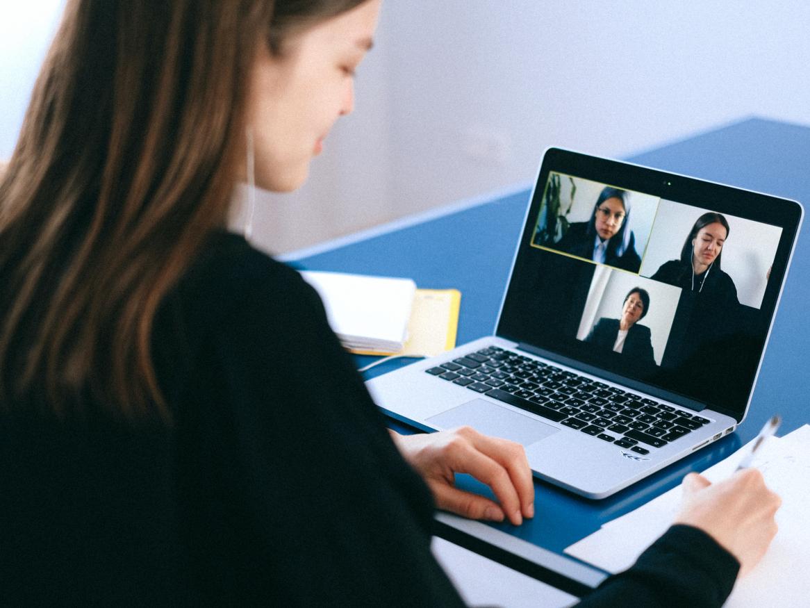 A video call, one person is in the room, three on the screen